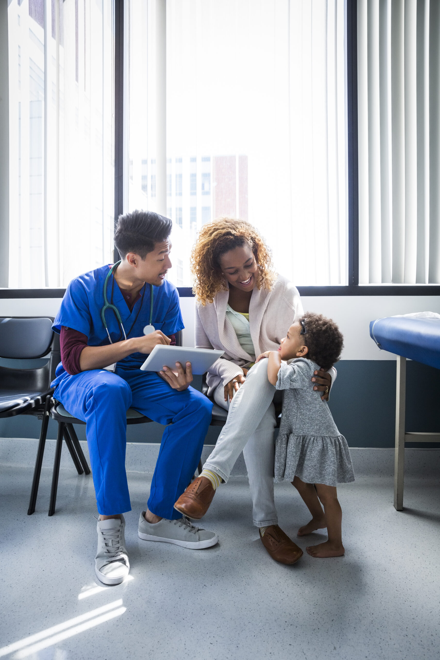 A doctor or nurse reading a chart to a mom and her small daughter