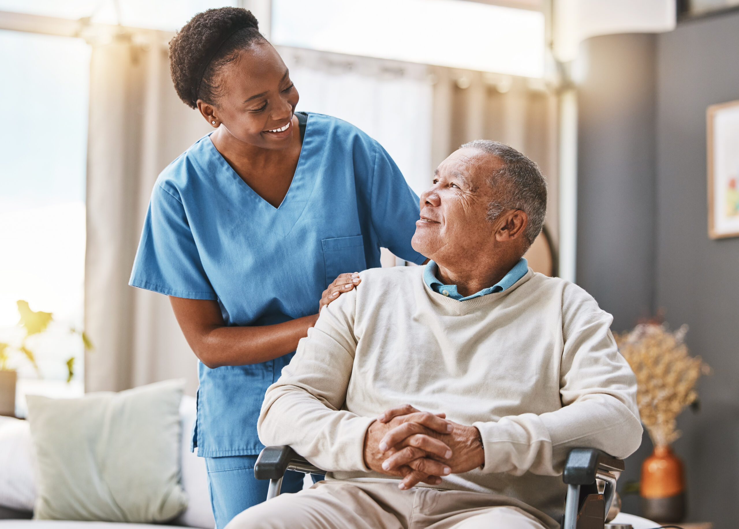 Nurse with older man in wheelchair smiling